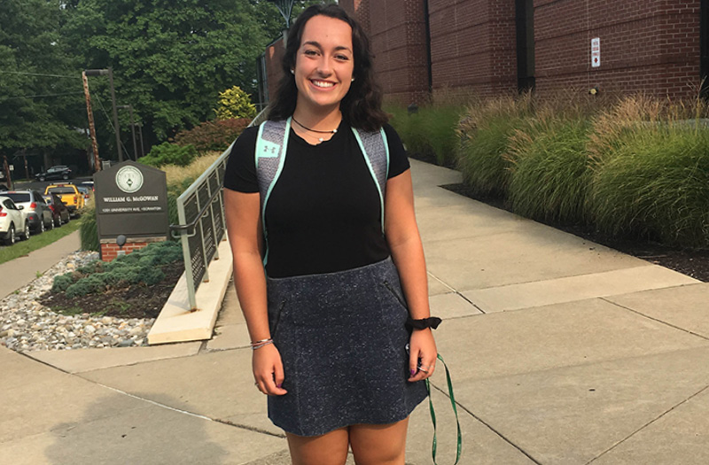 A young woman posing in front of Marywood University.